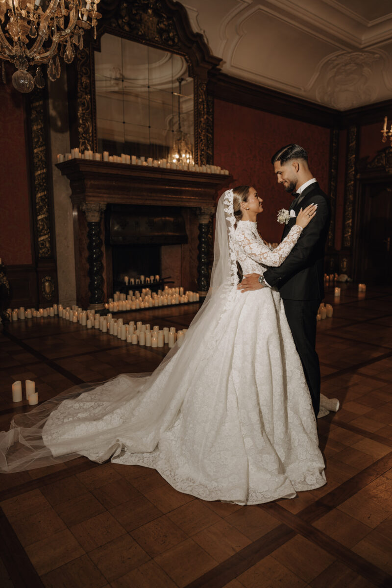 After Wedding Portfolio, Braut und Bräutigam stehen in einem roten Ballsaal wie zum Tanz voreinander, im Hintergrund sind viele Kerzen aufgestellt