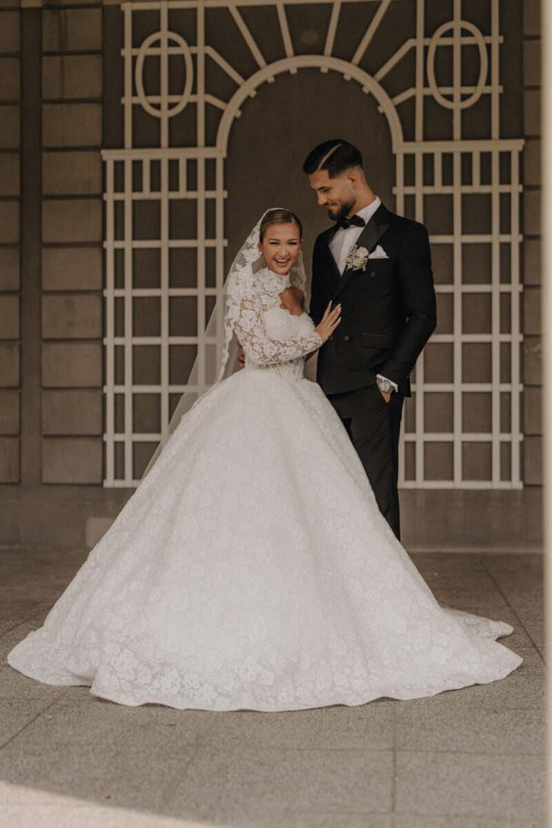 After Wedding Portfolio, Braut und Bräutigam stehen zueinander gewandt und während der Bräutigam seine Frau ansieht, schaut sie lachend zur Kamera