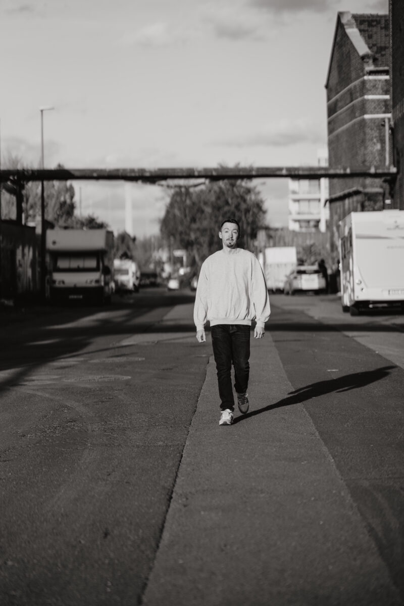 Schwarz-Weiß Portraitfoto eines Mannes, wie er die Straße lang schlendert