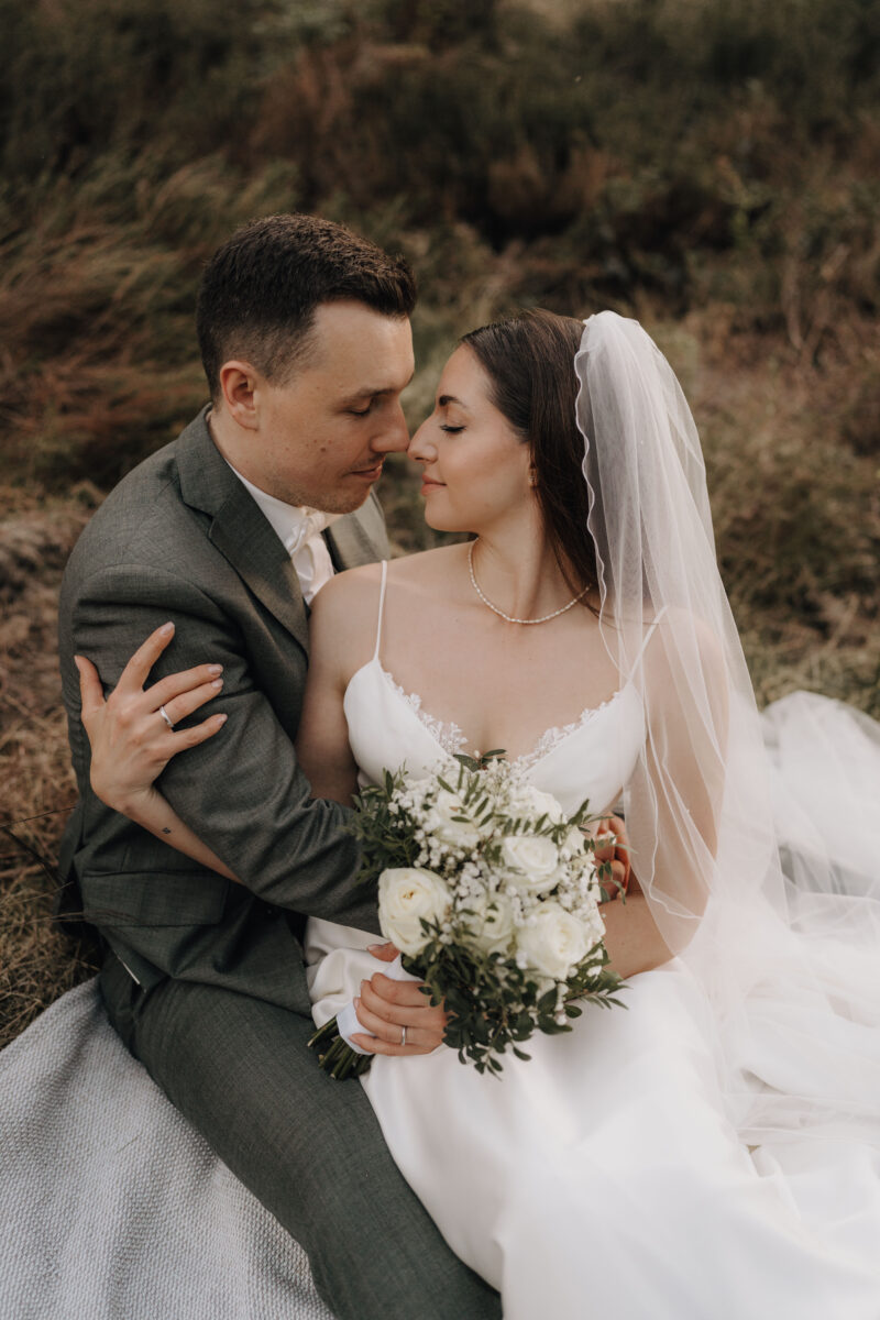 After Wedding Portfolio, Braut und Bräutigam sitzen Stirn an Stirn mit geschlossenen Augen in der Heide