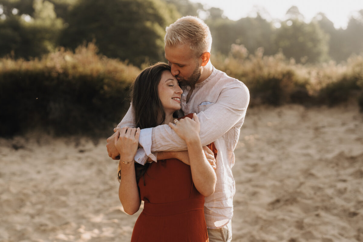 Sie wird von hinten umarmt und auf den Kopf geküsst