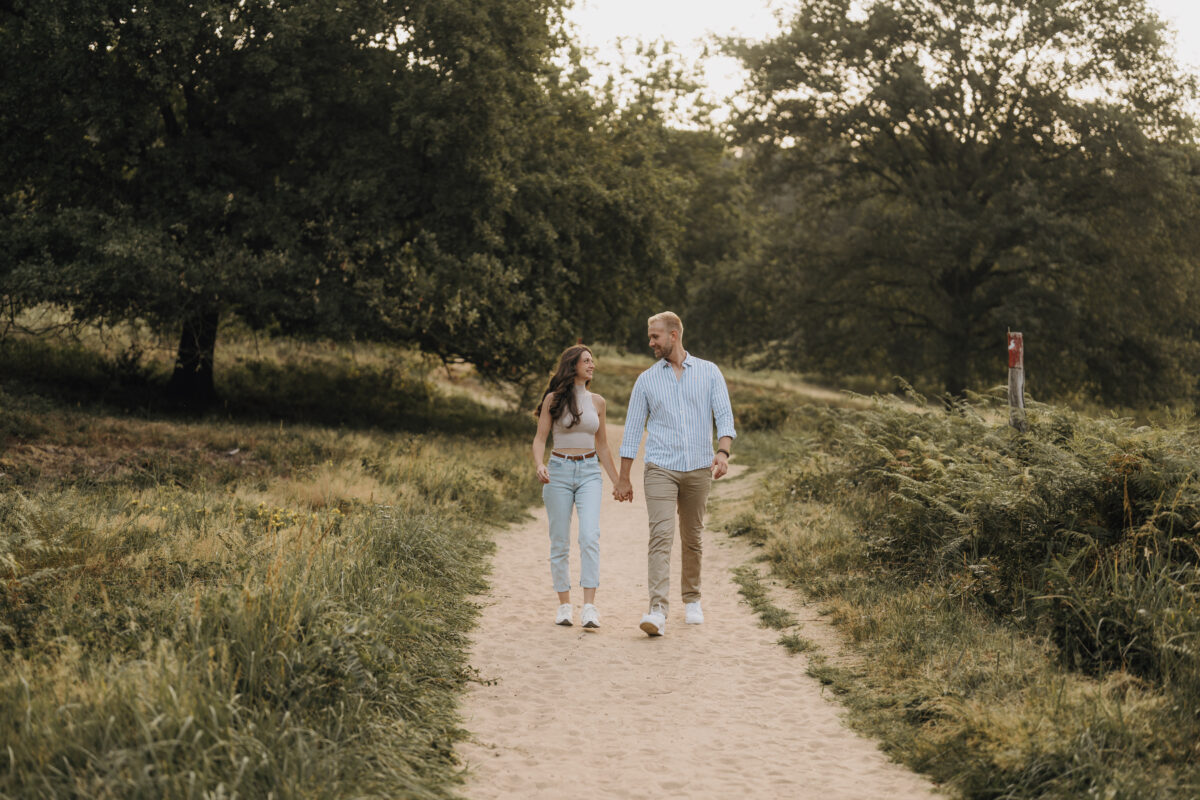 Paar spaziert Händchen haltend über eine Wiese und schaut sich an