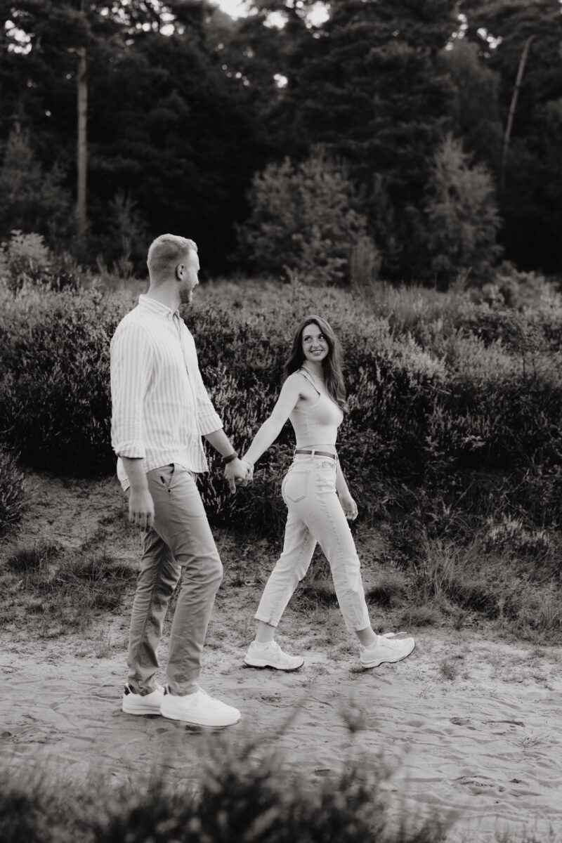 Paar schlendert durch den Wald und schaut sich an, fotografiert in Schwarz-Weiß