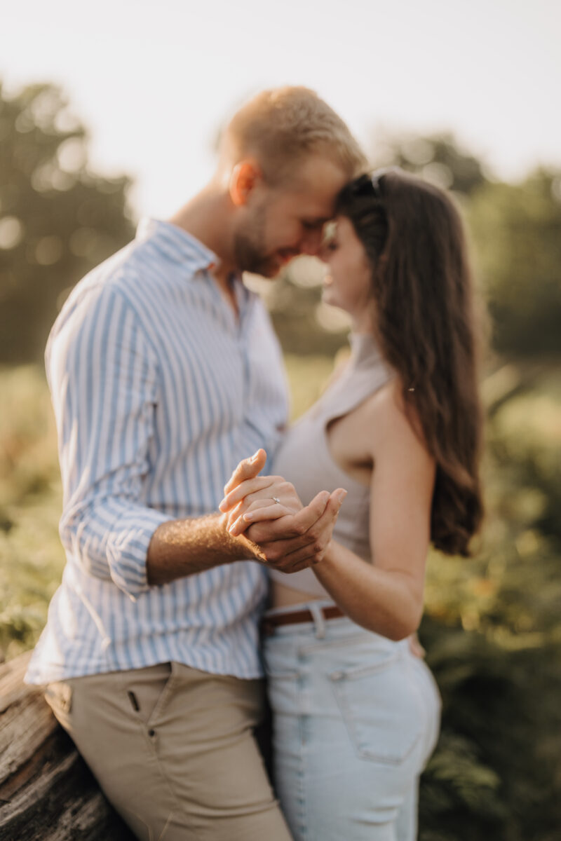 Paar steht Stirn an Stirn im Freien, ihre Hände sind im Fokus