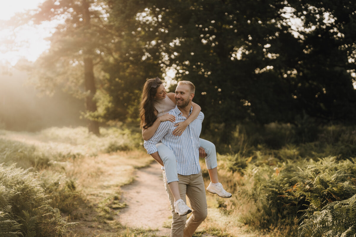 Paar läuft in der Abendsonne Huckepack über eine Wiese