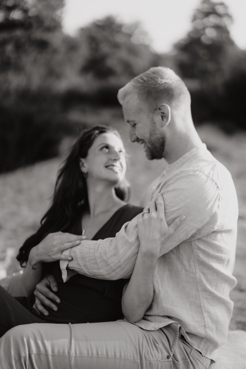 Paar liegt Arm in Arm und schauen sich verliebt in die Augen, fotografiert in Schwarz-Weiß