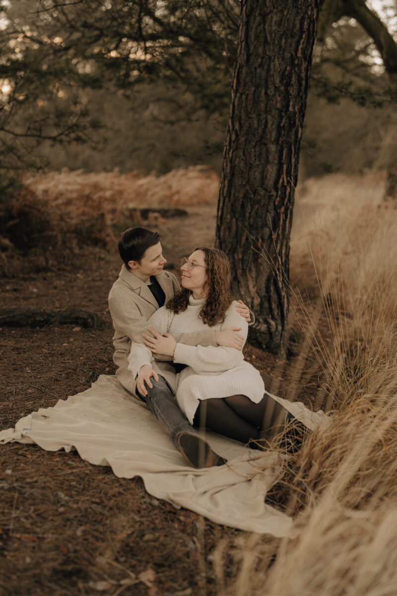 Paar liegt Arm in Arm auf einer Decke und schaut sich in die Augen
