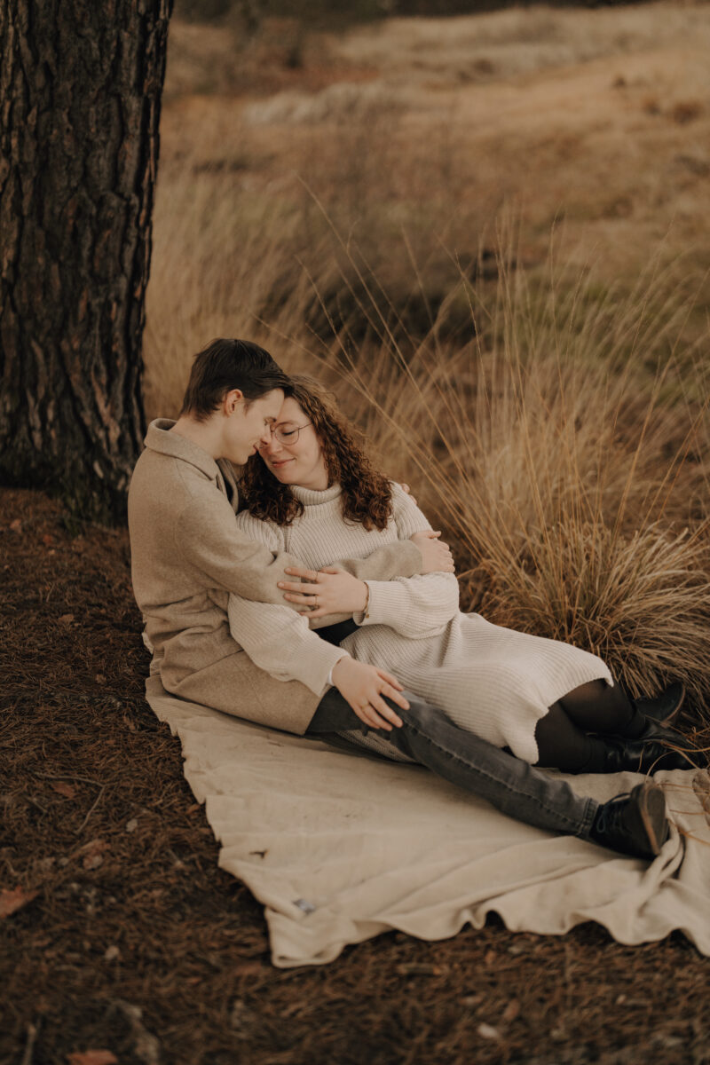 Paar liegt Arm in Arm auf einer Decke und schauen sich an