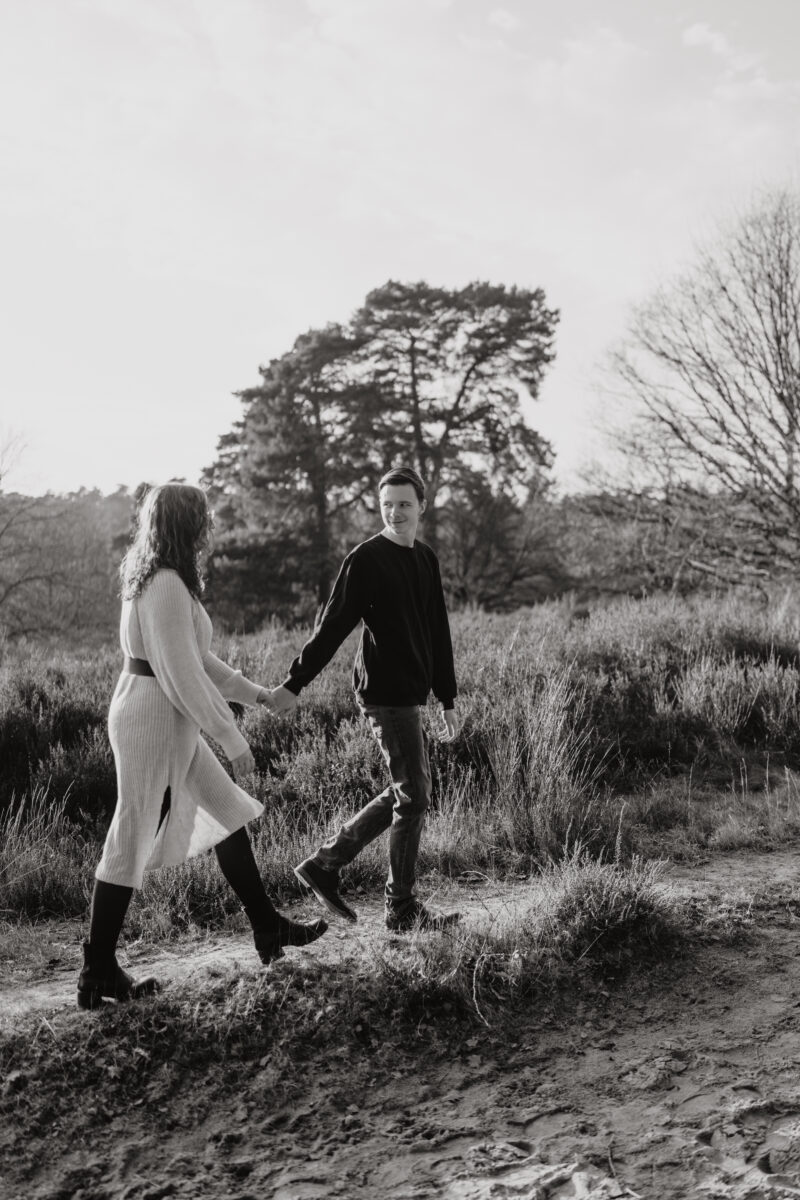 Paar schlendert Händchen haltend über die Wiese, fotografiert in Schwarz-Weiß