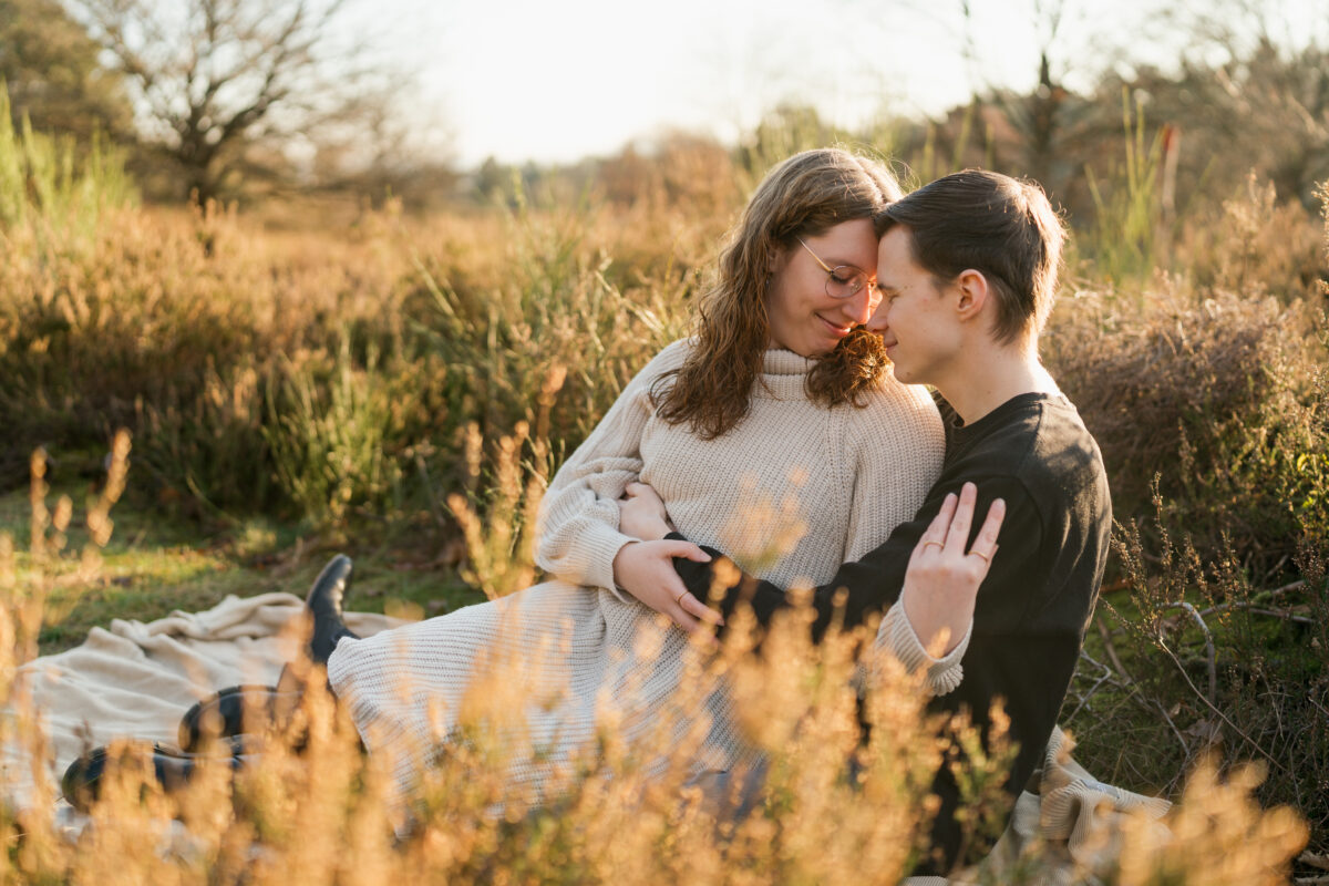 Paar liegt im Sonnenuntergang auf einer Wiese und schaut sich verliebt an
