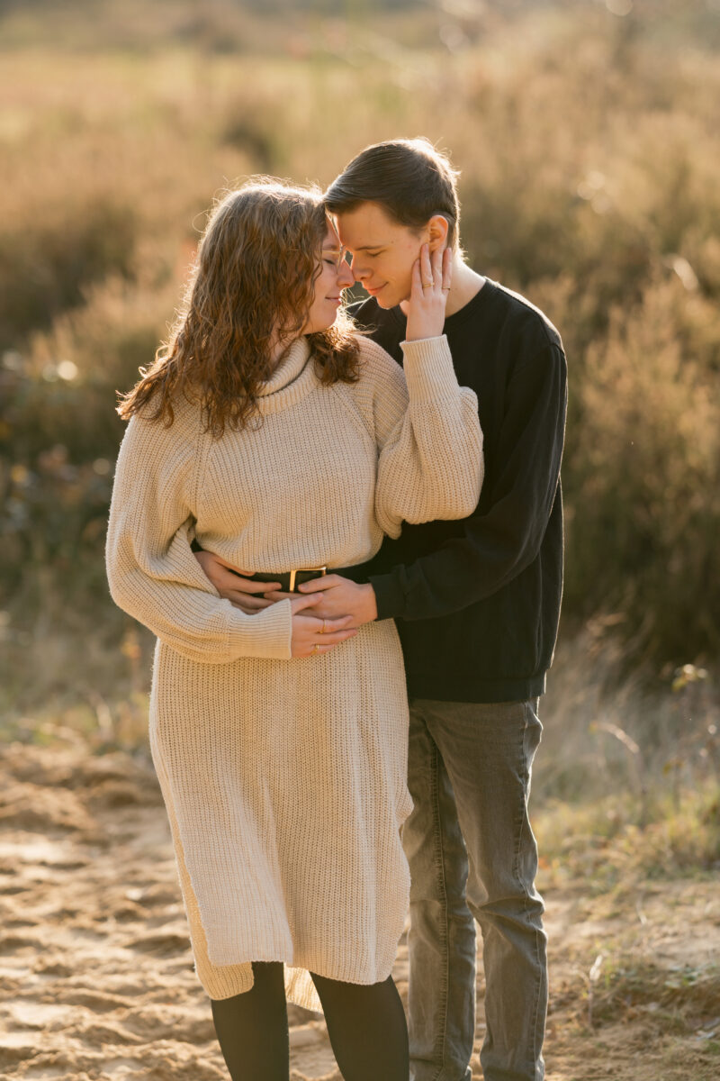 Sie wird von der Seite umarmt und setzt zum Kuss an