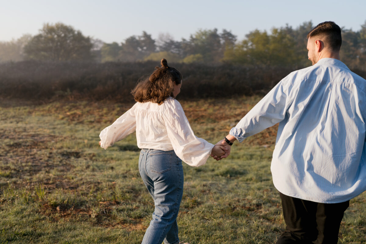 Paar läuft Händchen haltend über ein Feld