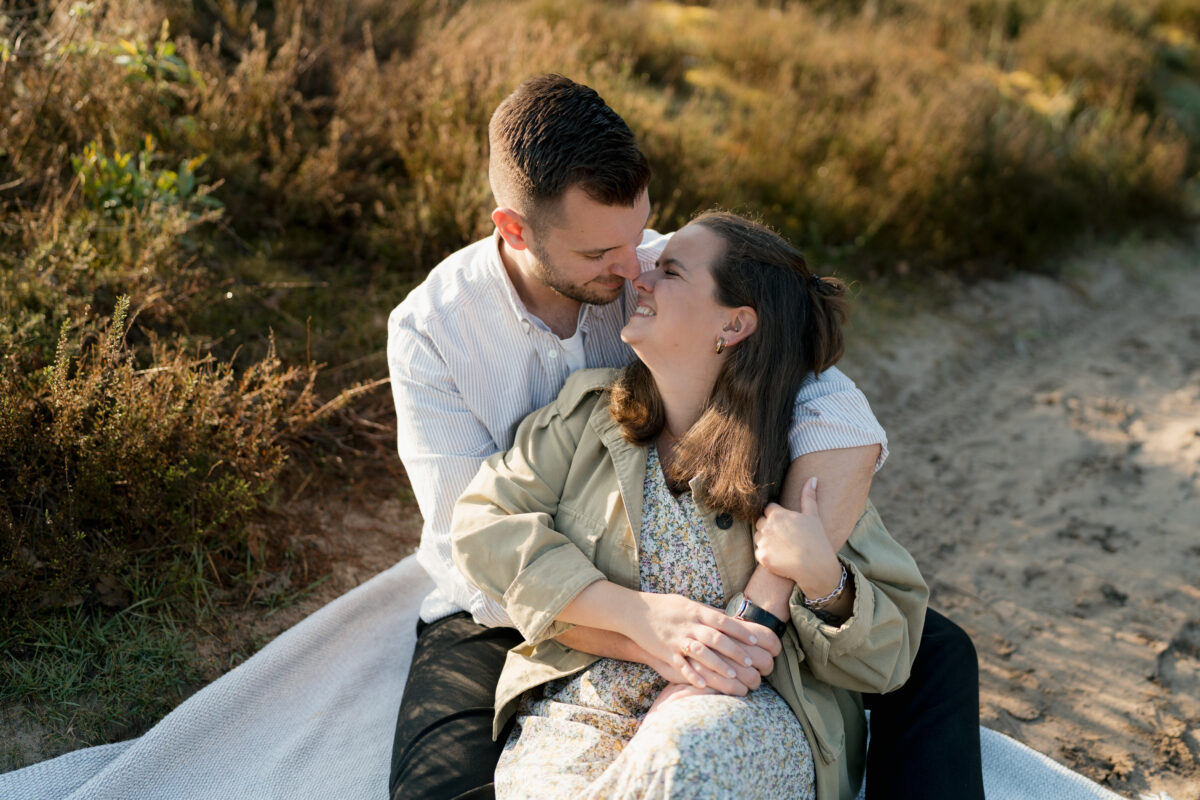 Paar sitzt Arm in Arm auf einer Decke und setzt zum Kuss an