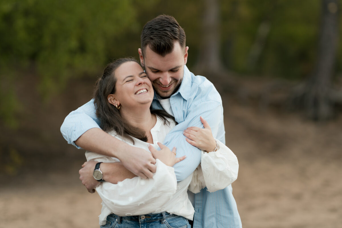 Er umarmt sie von hinten und lächelt