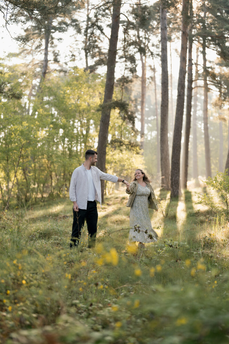 Paar geht Händchen haltend durch den Wald und schaut sich an