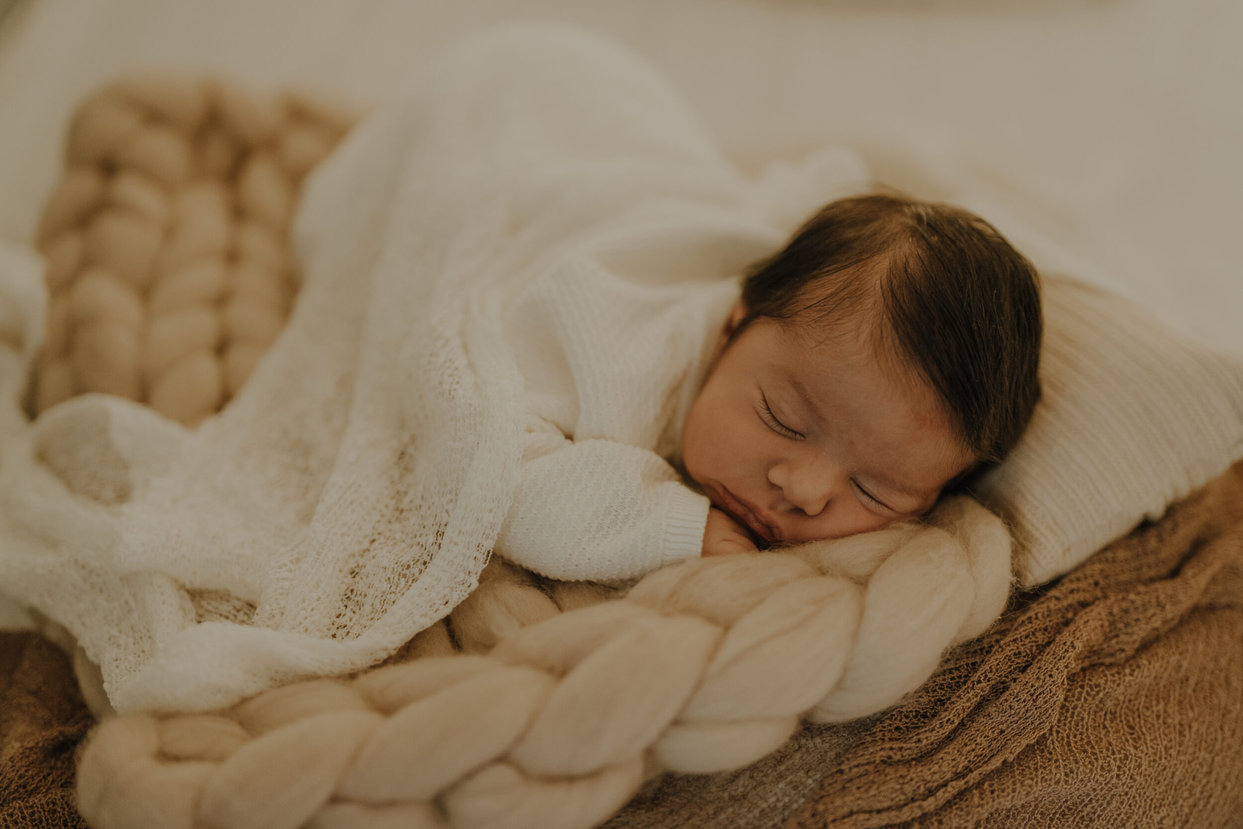 Newborn Portfolio Baby mit dunklem Haar schläft auf dem Bauch