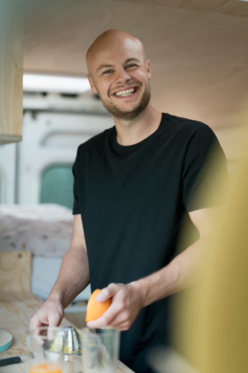 Portraitfoto eines Mannes, wie er in der Küche Orangensaft presst