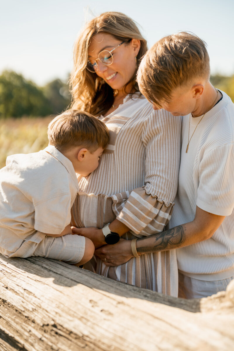 Babybauch Fotografie Portfolio schwangere Frau mit zwei Kindern posiert in der Natur