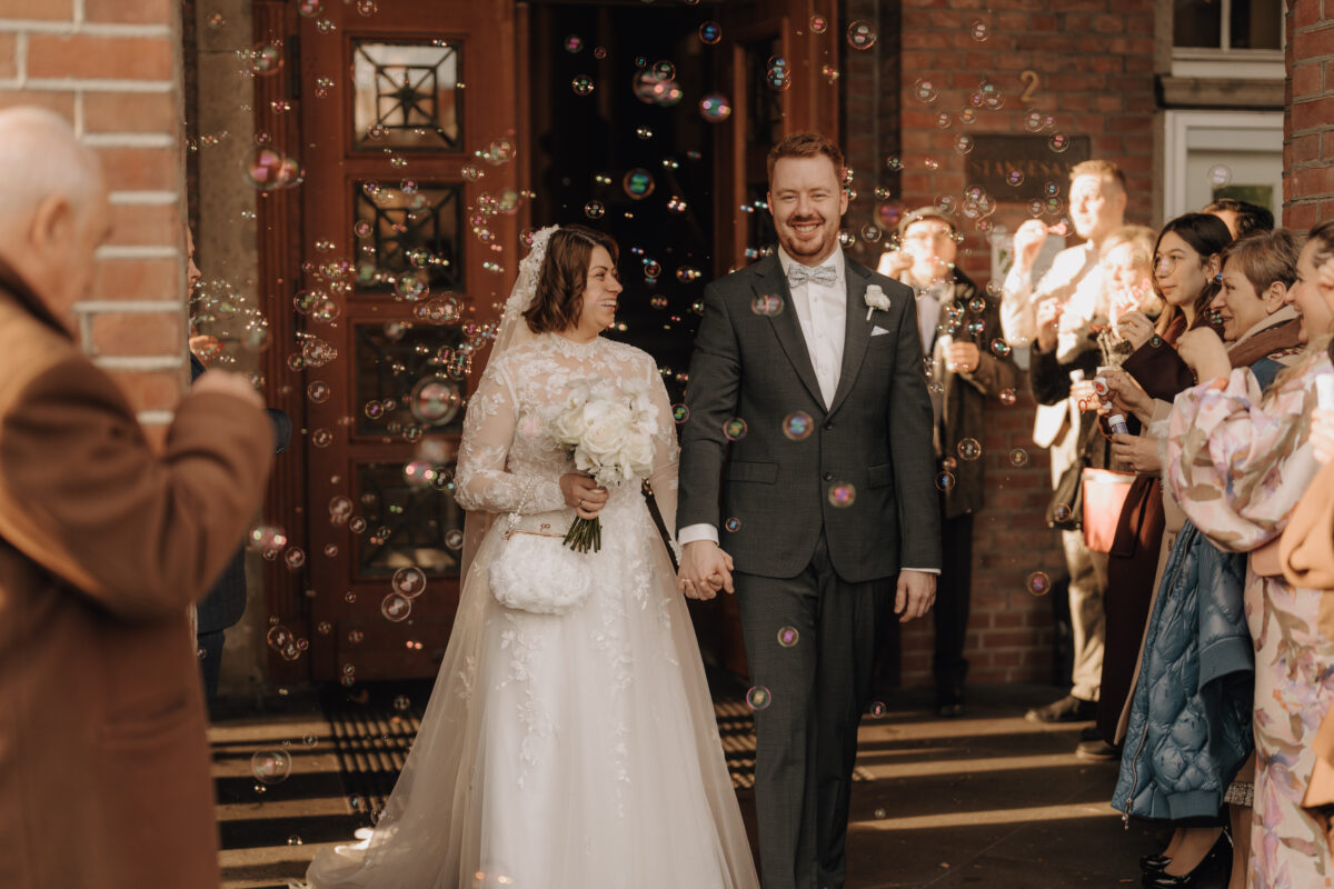 Hochzeitsportfolio, Braut und Bräutigam laufen gemeinsam aus der Trauung raus und wurden mit Seifenblasen begrüßt