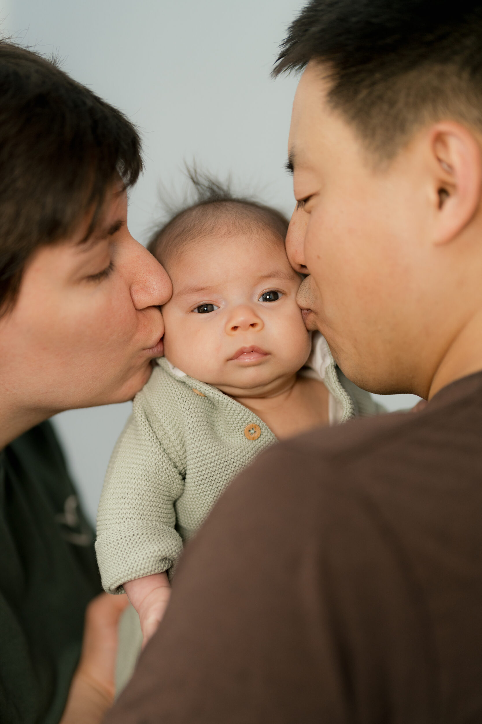 Newborn Portfolio Baby in der Mitte wird von Mama und Papa liebkost