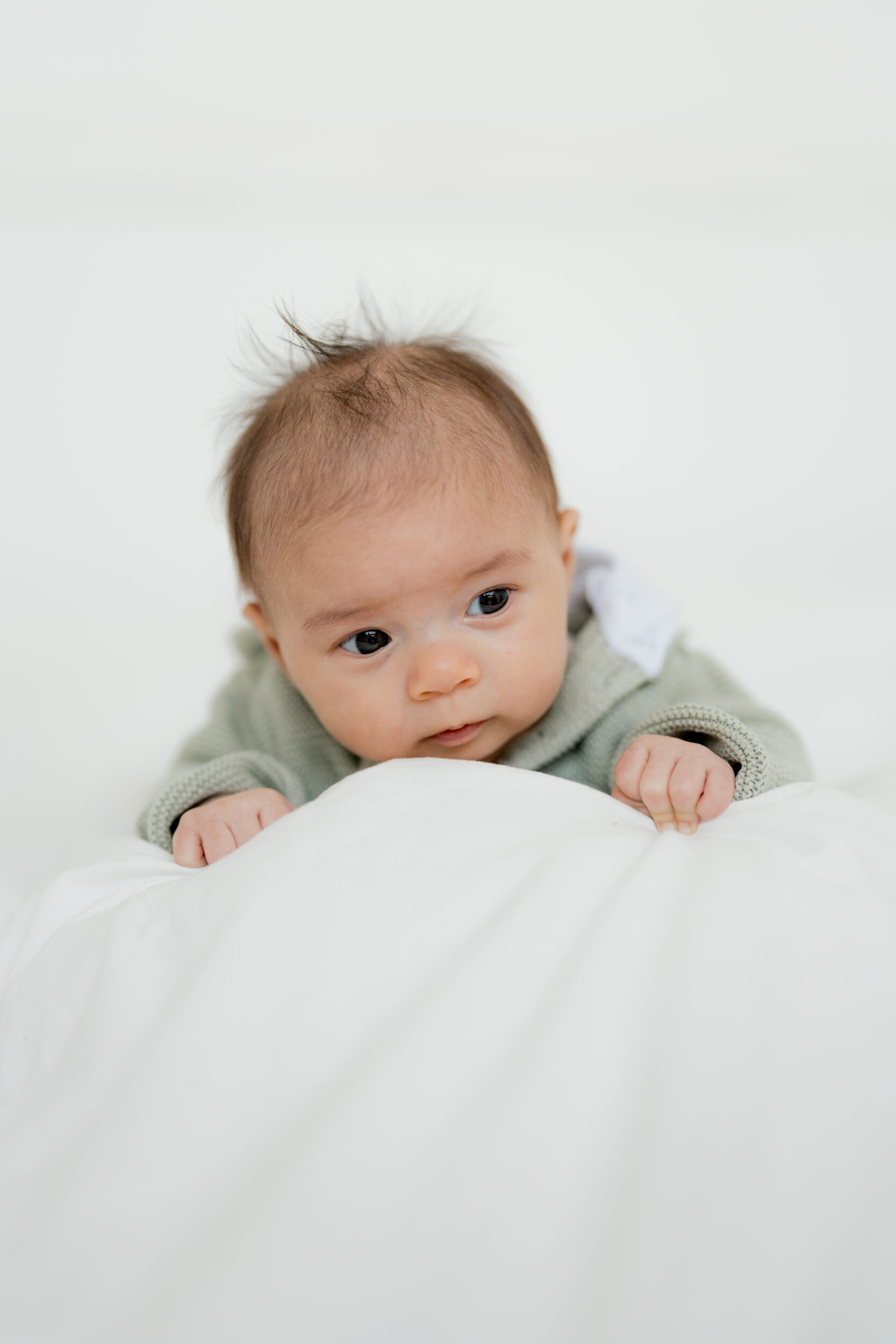 Newborn Portfolio Baby auf weißer Bettdecke von vorne