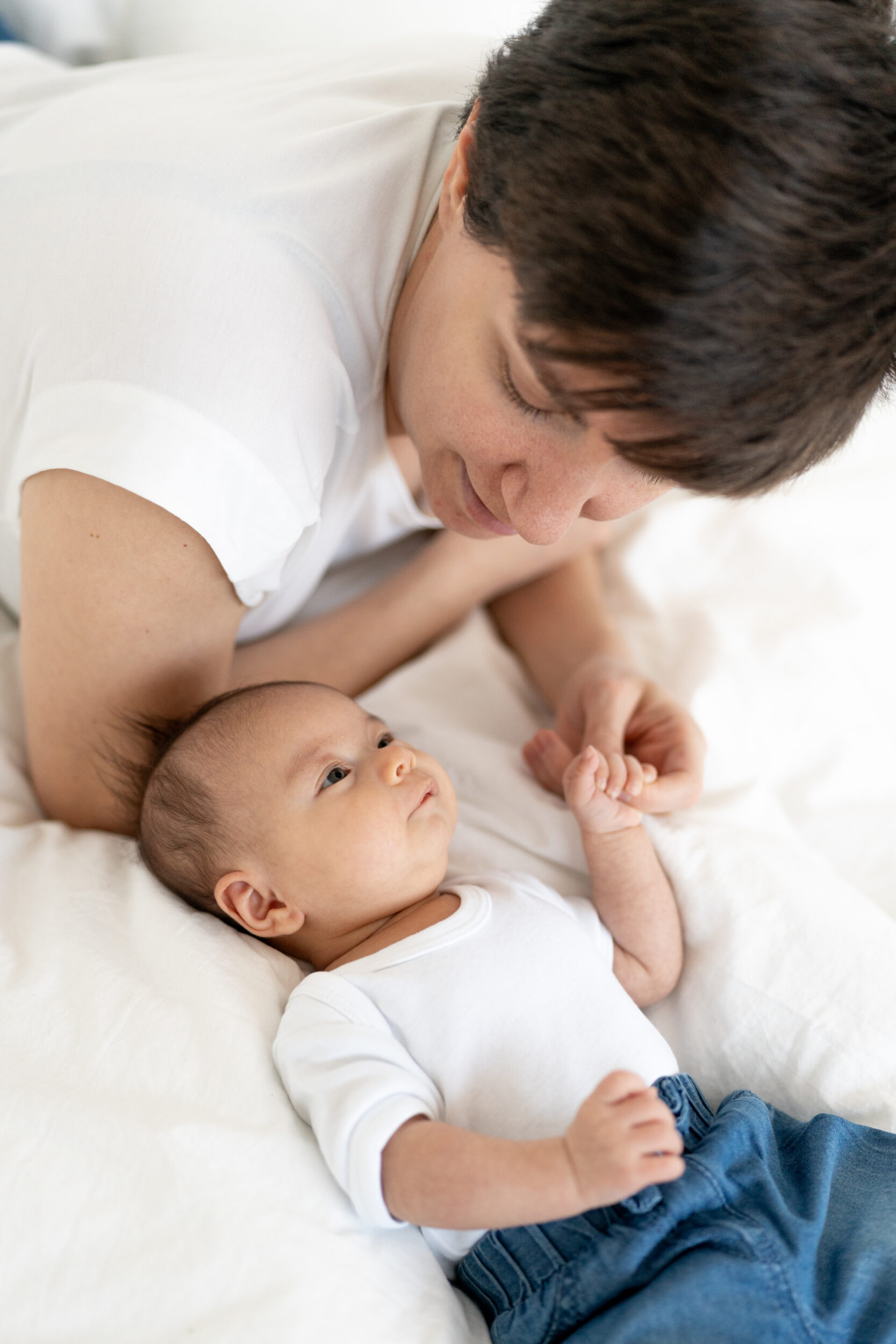 Newborn Portfolio Baby mit Mama auf weißer Bettdecke