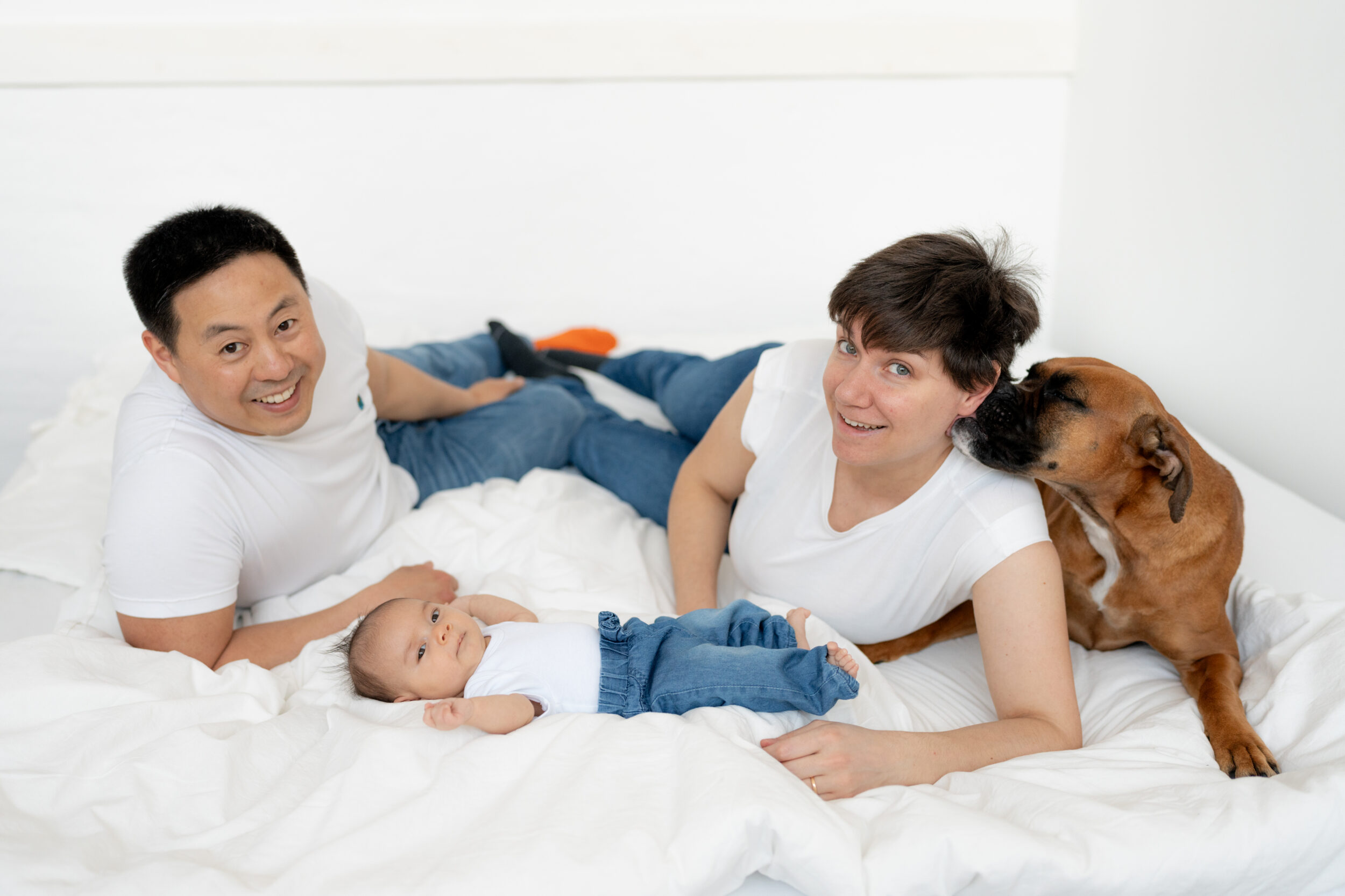 Newborn Portfolio Baby Mama, Papa und Hund auf weißer Bettdecke