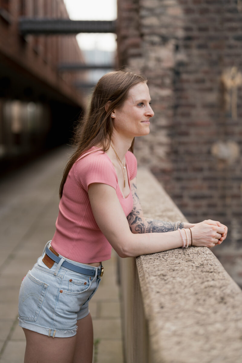 Portraitfoto einer Frau, die über eine mauer lehnt und lächelt