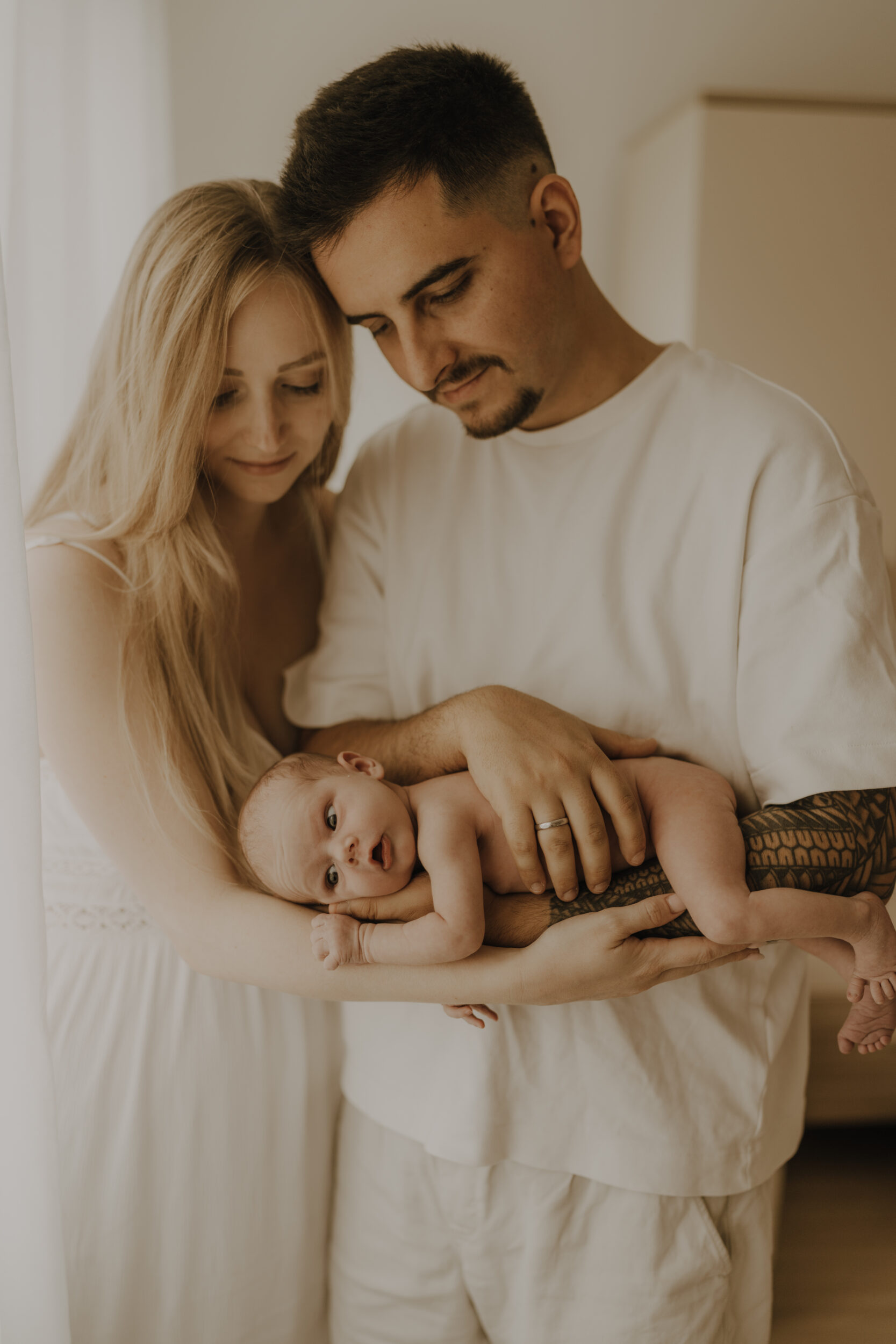 Newborn Portfolio Baby liegt mit dem Bauch auf Mamas und Papas Arm