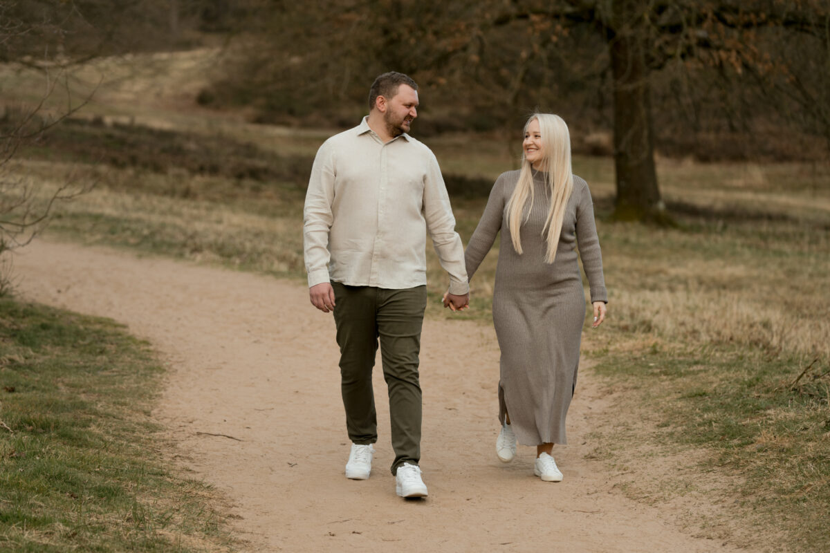 Paar schlendert Händchen haltend durch den Sand und schaut sich an