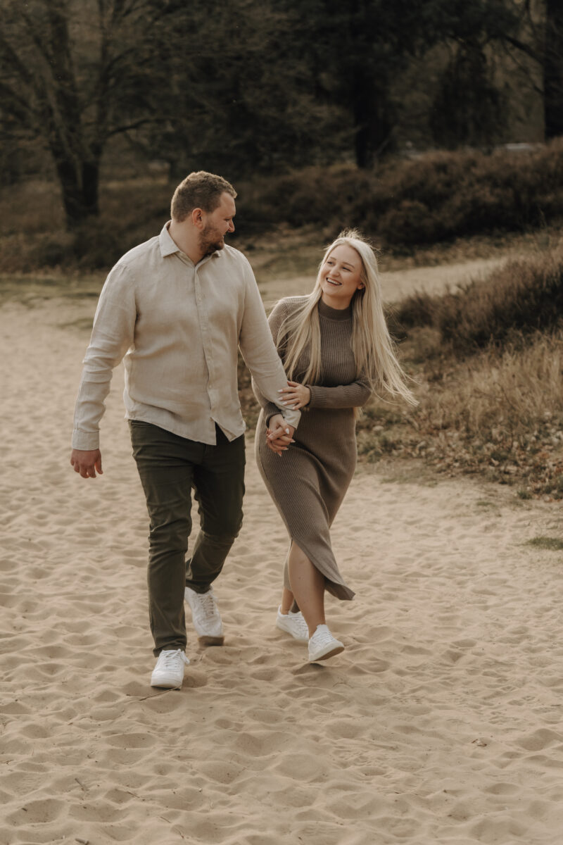 Paar schlendert Händchen haltend durch den Sand