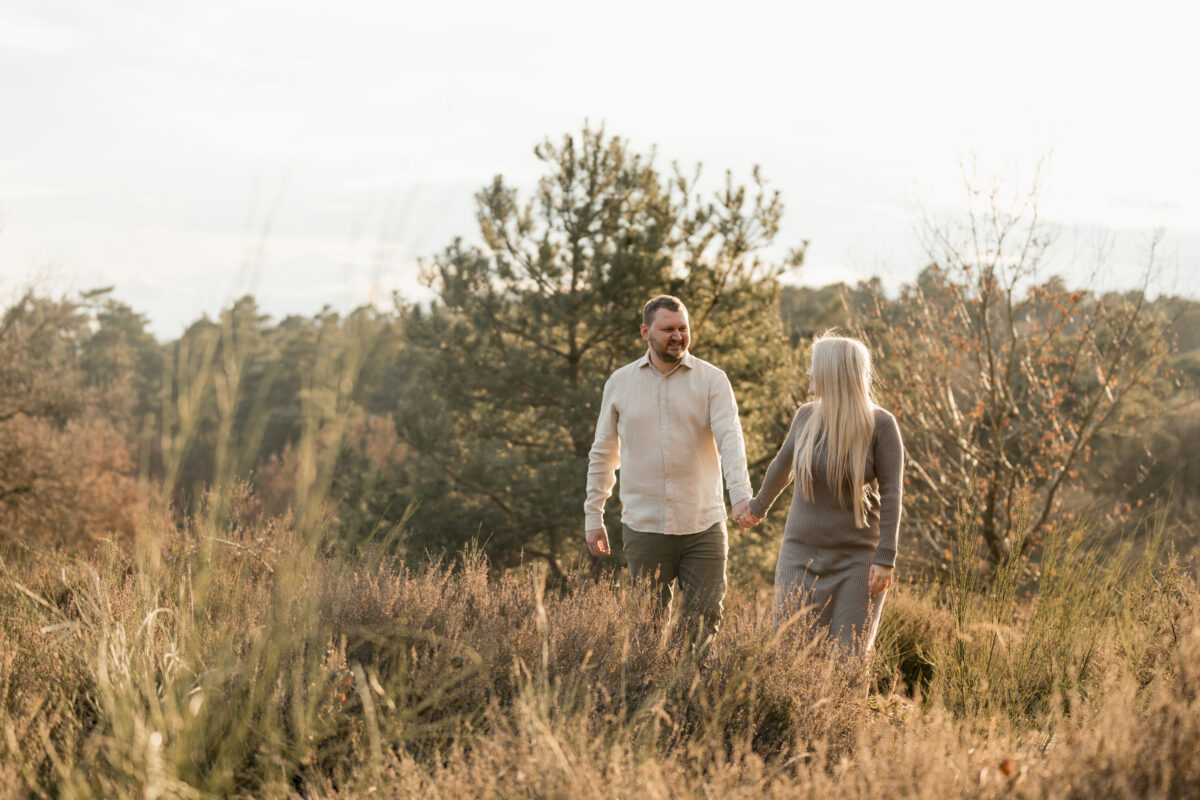 Paar läuft Händchen haltend durchs Feld