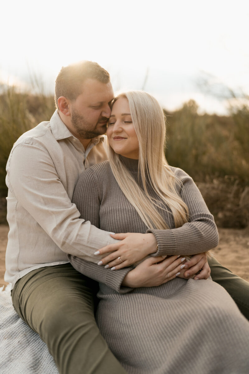 Paar sitzt Arm in Arm auf einer Decke und setzt zum Kuss an