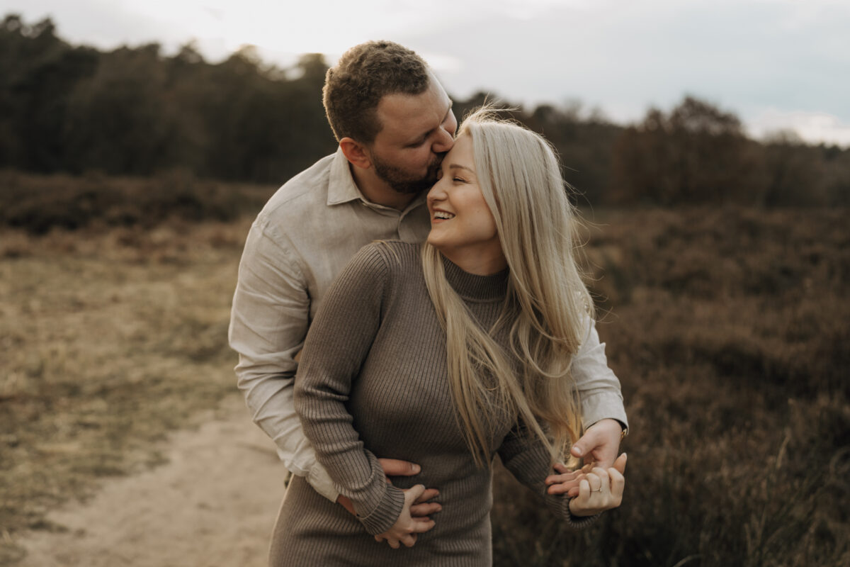 Er küsst ihre Stirn von hinten, sie lacht