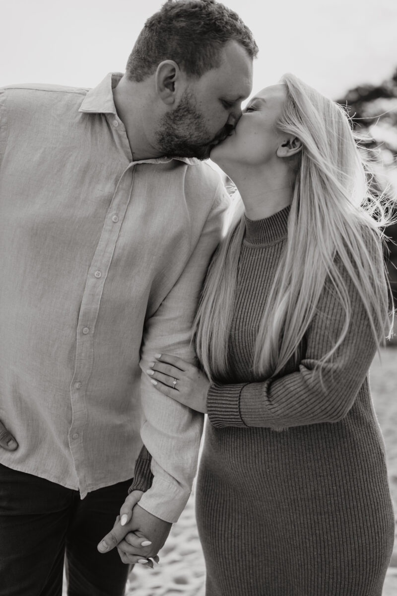 Paar küsst sich im Gehen, fotografiert in Schwarz-Weiß