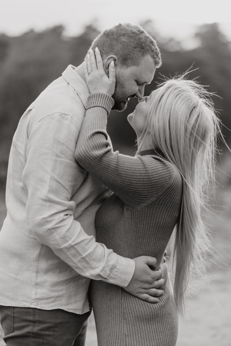 Paar schaut sich verliebt in die Augen und setzt zum Kuss an, fotografiert in Schwarz-Weiß