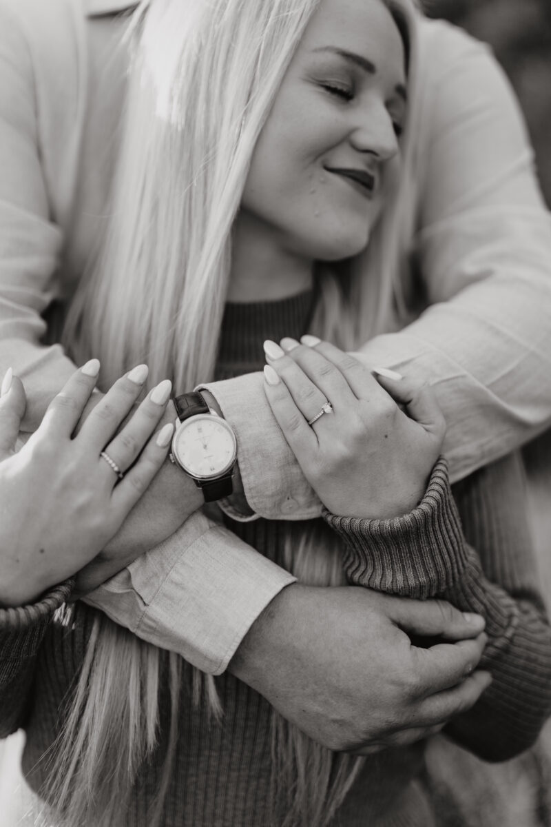 Er umarmt sie von hinten, Fokus auf ihre Hände