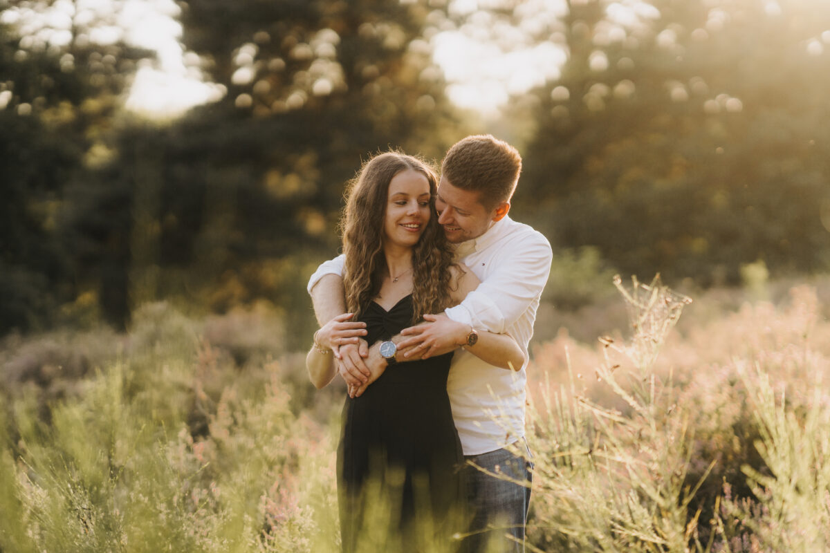 Er umarmt sie von hinten und lächelt