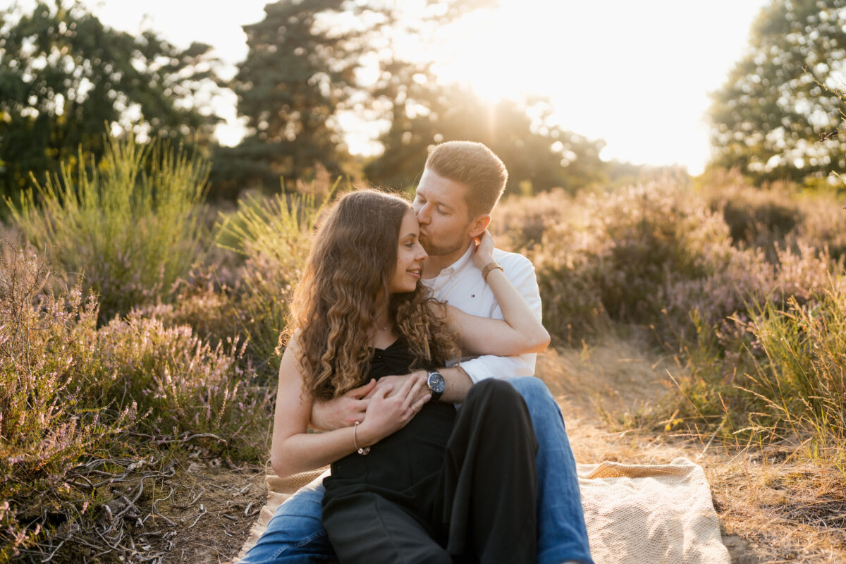 Paar liegt Arm in Arm auf einer Decke in der Abendsonne