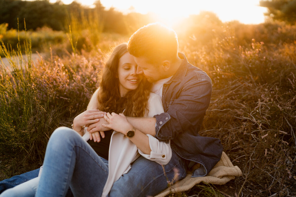 Paar liegt Arm in Arm auf einer Decke in der Abendsonne