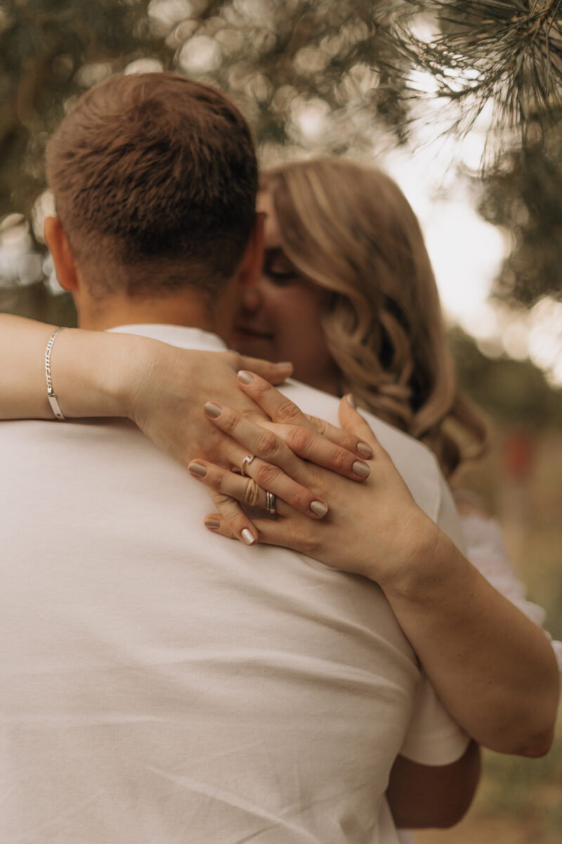 Paar umarmt sich, Ihre Hand liegt auf seinem Rücken im Fokus