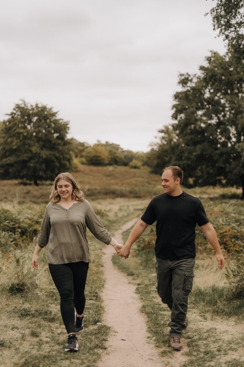 Paar schlendert Händchen haltend über eine Wiese