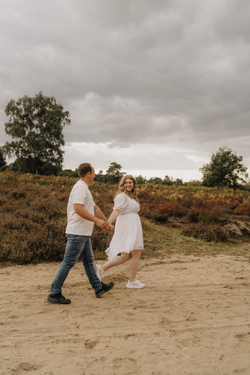 Paar läuft Händchen haltend im Sand und schaut sich an