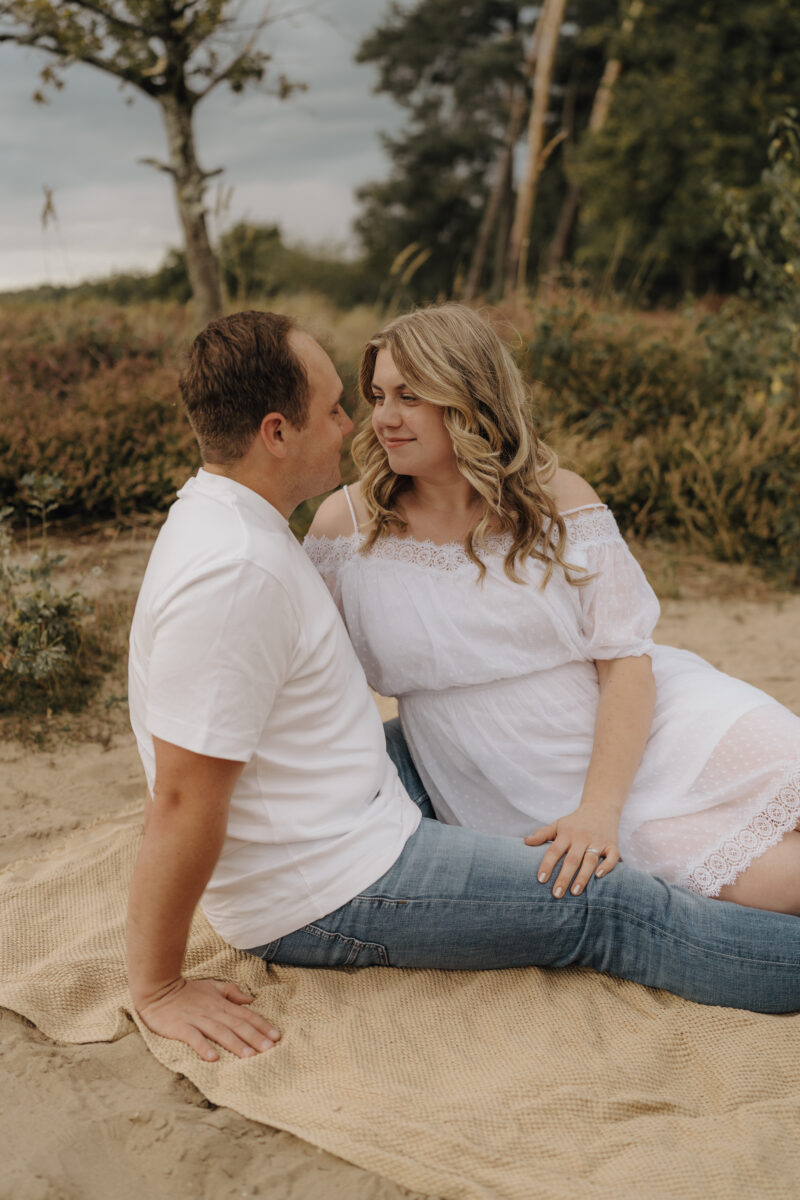 Paar sitzt Arm in Arm auf dem Boden und schauen sich verliebt an