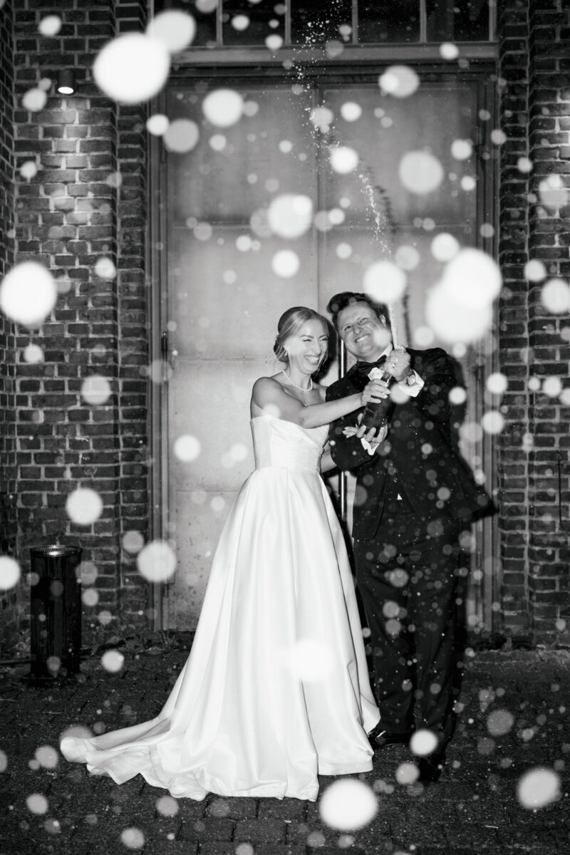 Hochzeitsportfolio, Braut und Bräutigam feiern ausgelassen mit einem Sektanstoß