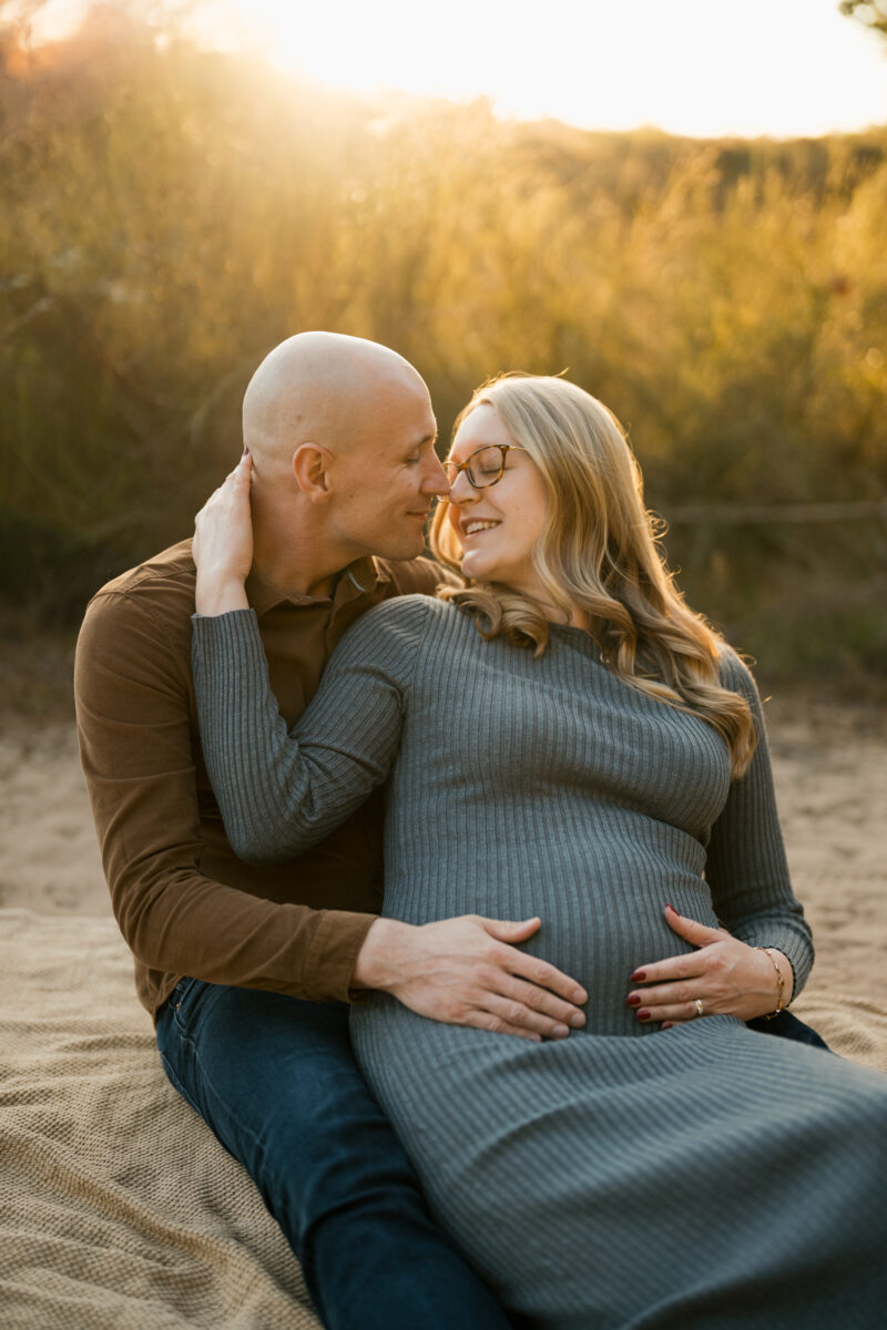 Babybauch Fotografie Portfolio verliebtes Paar posiert Arm in Arm in der Natur