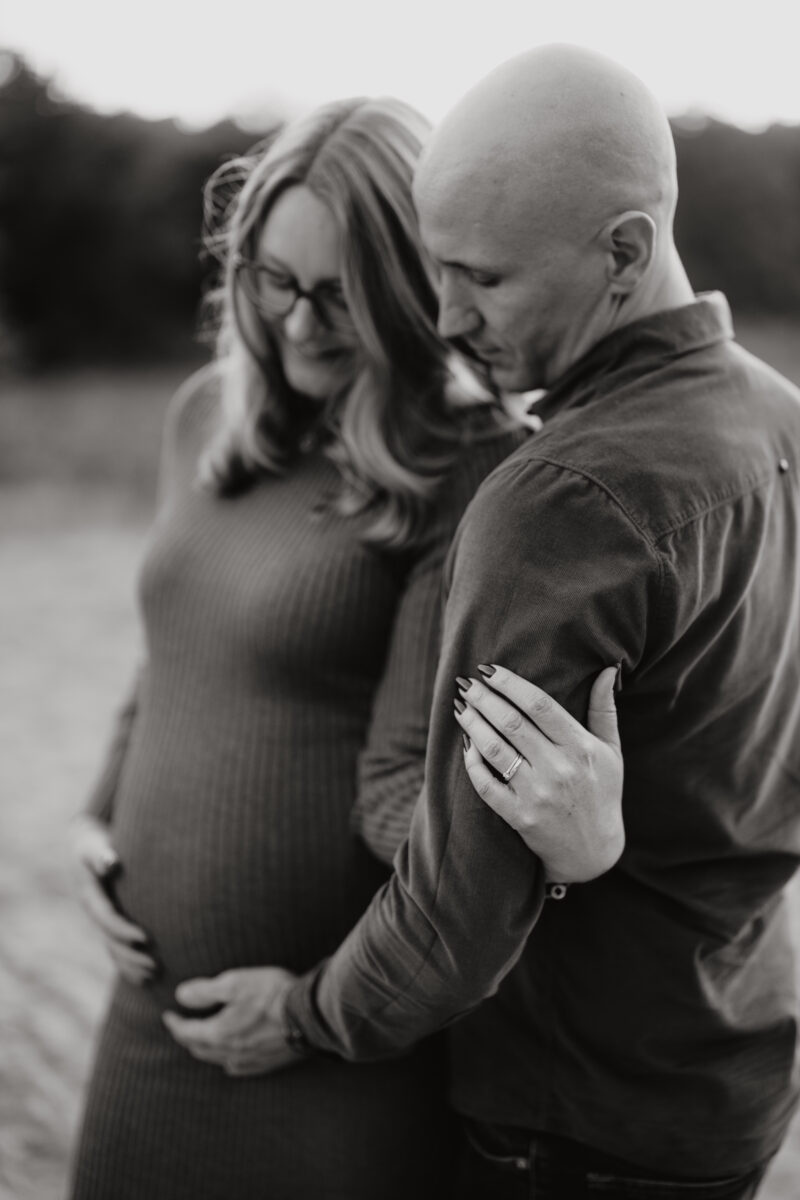 Babybauch Fotografie Portfolio Paar schaut herab auf den Babybauch Schwarz-Weiß-Fotografie