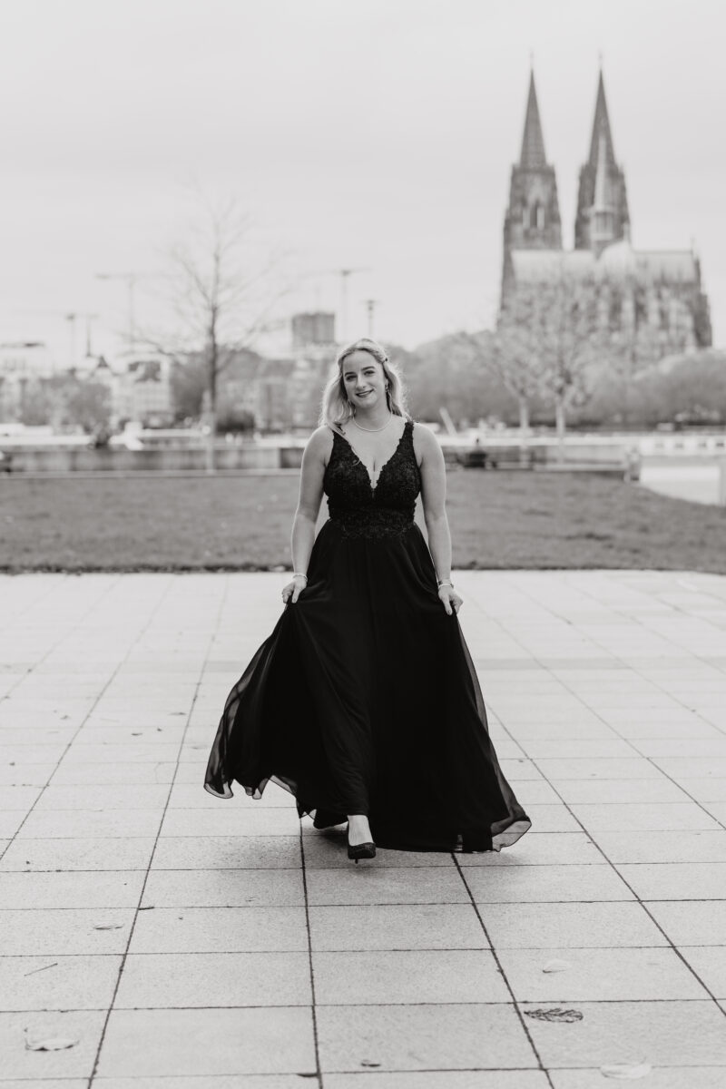 Schwarz-Weiß Portraitfoto einer Frau im Abendkleid, im Hintergrund der Kölner Dom