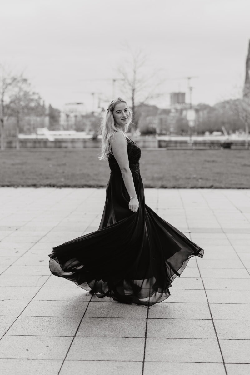 Schwarz-Weiß Portraitfoto einer Frau in Abendkleid, in schwungvoller Drehung