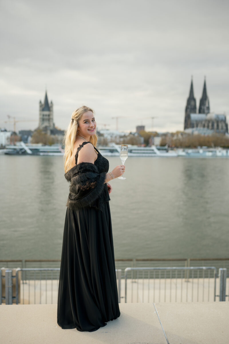 Portraitfoto einer Frau mit Abendkleid und Sekt Glas in der Hand